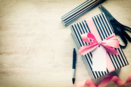 Gift box and wrapping materials on a white wood old background. Greeting note tied over. Vintage style.の写真素材