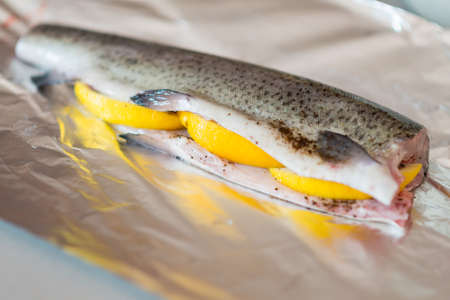 Fresh trout fish prepared to be cooked over aluminium foil with lemon and spices.の写真素材