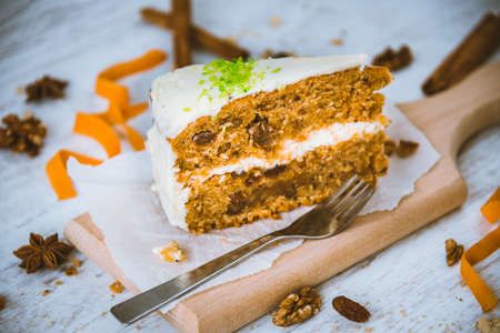 Close up of a homemade carrot cake with raisins, walnuts and cinnamon over white wooden background. Cream cheese frosting.の写真素材