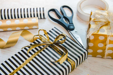Close up of gift boxes wrapped in black and white striped and golden dotted paper and wrapping...
