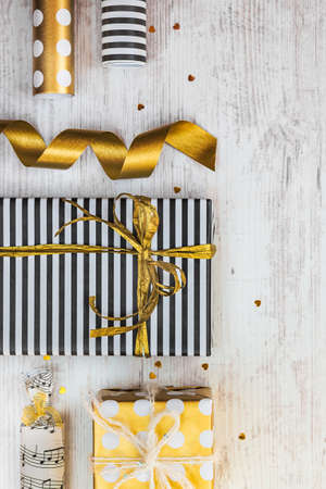 Gift boxes wrapped in black and white striped and golden dotted paper and wrapping materials on a...