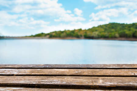 Close view of an old wooden table. Blue lake and sky in the background.の写真素材