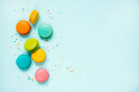 Colorful macaroons and sugar sprinkles arranged over blue background. Copy space.の写真素材