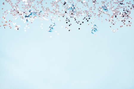 Star shaped silver sequins and silver ribbons over blue background. Copy space.の写真素材