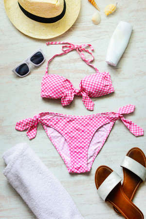 Top view of two pieces pink swimming suit and beach accessoties over wooden background.の写真素材