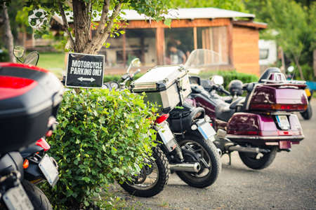 A row with parked motorcycles in a camping area with a "Motorcycle parking only" sign.の写真素材