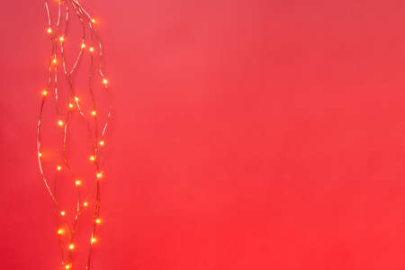 Christmas lights garland border over red background. Flat lay, copy space.の写真素材