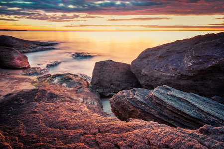 Picturesque sunrise over a rocky beach.の写真素材