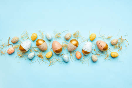 Top view of easter eggs colored with golden paint and differen colors. Blue background. Copy space.