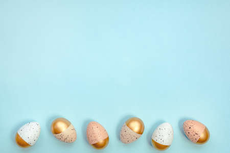 Top view of easter eggs colored with golden paint and different colors. Blue background. Copy space.