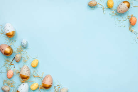 Top view of easter eggs colored with golden paint and differen colors. Blue background. Copy space.の写真素材