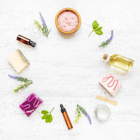 Top view of organic soaps and cosmetics arranged in circle with lavender, herbs, chia seeds and essential oils. White rusric background, copy space.の写真素材