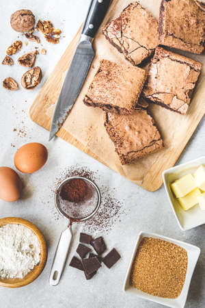 Top view of freshly baked home made brownie cake arranged with recipe ingredients over white rustic background.の写真素材