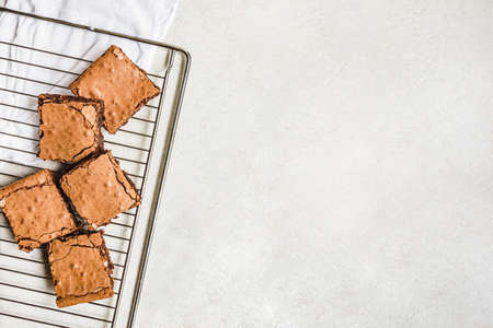 Top view of freshly baked home made brownie cake cut in squares over a backing rack. Copy space.