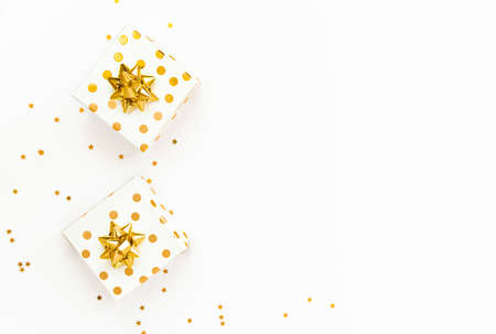 Top view of a golden dotted gift boxes and star shaped golden sequins on a white background. Copy...