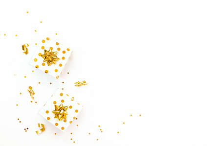 Top view of golden dotted gift boxes and star shaped golden confetti on a white background. Copy...