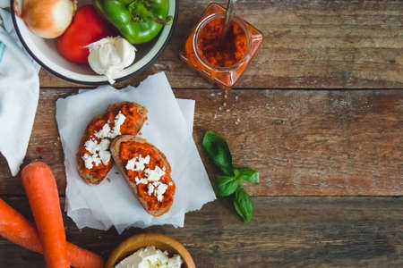 Wholegrain bread covered with tomato-pepper dip and feta cheese over old rustic wooden table. Homemade organic vegetable dish.の写真素材