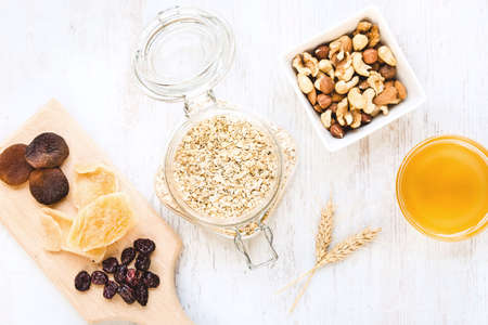 Top view of raw ingredients for homemade granola preparation - oats, nuts, honey and dried fruits. Healthy eating.の写真素材