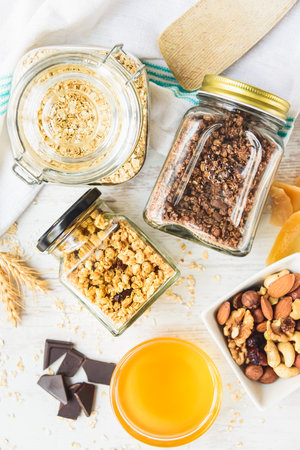 Top view of jars full of oats and various crunchy granola - plain, dried fruits, nuts and chocolate. Healthy eating concept.の写真素材