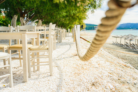 Beach restaurant with all white colored furniture in front of the fascinating golden turquoise colors of the sand and sea. Bright sunny day.の写真素材