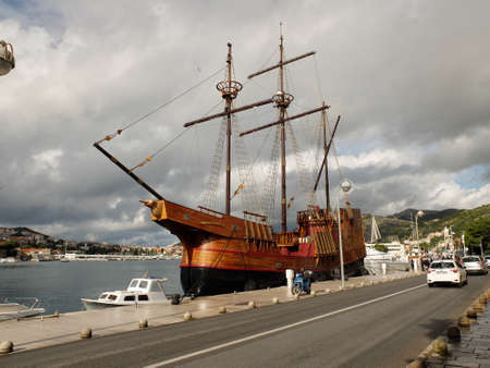 DUBROVNIK, CROATIA . A fishing boat moored at the harbor of the port in the town against the background of buildingsのeditorial素材