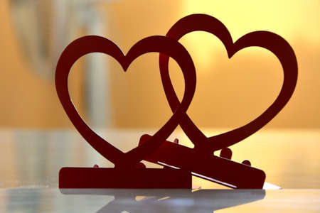 Vibrant red candlesticks in form of hearts casting shadow on table in daylight on blurred background