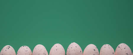 Top view background of row of artificial eggs with spots on dark turquoise background