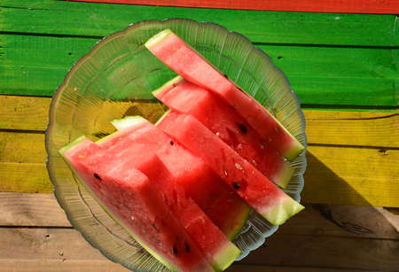 Watermelon cut into slices on a multi colored backgroundの写真素材