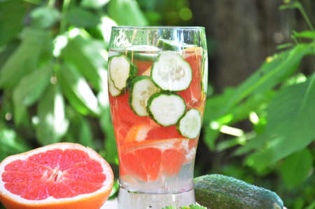 Summer fresh fruit Flavored infused water mix of grapefruit and cucumber with lemon on the background of foliageの写真素材