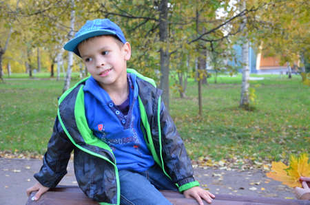 Teenager with mother sitting on bench in autumn parkの写真素材
