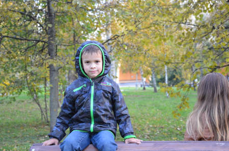 Teenager with mother sitting on bench in autumn parkの写真素材