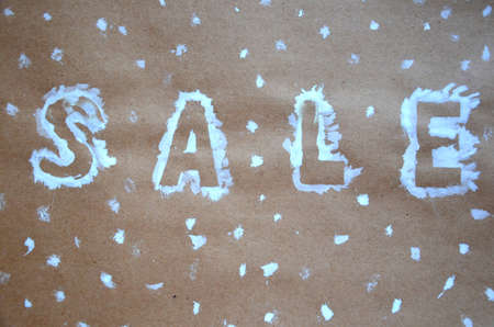 An inscription of a sale on a Christmas background. new year decoration. on kraft paper. Christmas boxes in snow with sale tag. christmas treeの写真素材