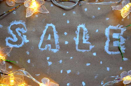 An inscription of a sale on a Christmas background. new year decoration. on kraft paper. Christmas boxes in snow with sale tag. christmas treeの写真素材