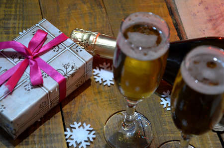 two glasses of champagne on the background of champagne. Christmas tree with Christmas lights. New Year and Christmas. Gift boxes tied with bowsの写真素材