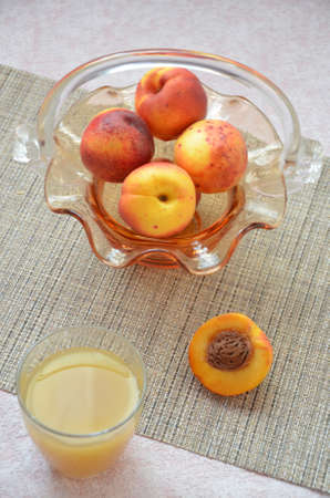 Ripe peaches and glass of juice on a table, cut peach, of a beautiful vase in the shape of a basket backgroundの写真素材