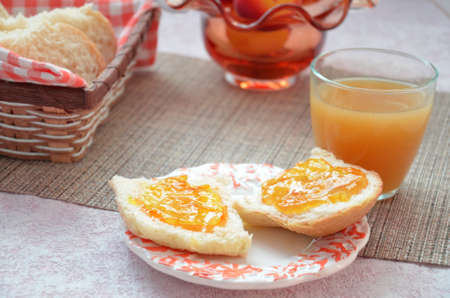 Healthy breakfast ingredients. Bowl of oat granola. beautiful fresh tasty Breakfast on the table. white bread toast basket sliced. sandwich with jam. peach juice. fresh fruit peaches.の写真素材