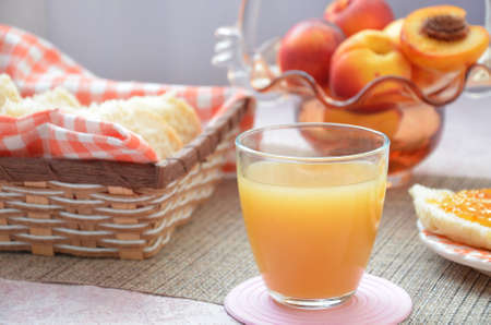Healthy breakfast ingredients. Bowl of oat granola. beautiful fresh tasty Breakfast on the table. white bread toast basket sliced. sandwich with jam. peach juice. fresh fruit peaches.の写真素材