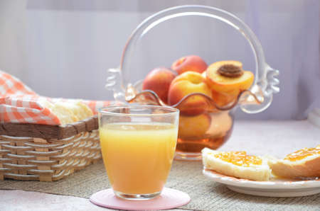 Healthy breakfast ingredients. Bowl of oat granola. beautiful fresh tasty Breakfast on the table. white bread toast basket sliced. sandwich with jam. peach juice. fresh fruit peaches.の写真素材