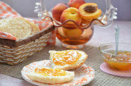 Healthy breakfast ingredients. Bowl of oat granola. beautiful fresh tasty Breakfast on the table. white bread toast basket sliced. sandwich with jam. peach juice. fresh fruit peaches.の写真素材