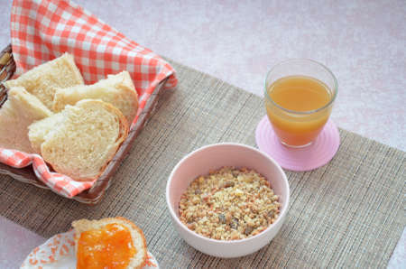 Healthy breakfast ingredients. Bowl of oat granola. beautiful fresh tasty Breakfast on the table. white bread toast basket sliced. sandwich with jam. peach juice. fresh fruit peaches.の写真素材