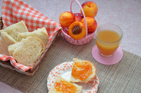 Healthy breakfast ingredients. Bowl of oat granola. beautiful fresh tasty Breakfast on the table. white bread toast basket sliced. sandwich with jam. peach juice. fresh fruit peaches.の写真素材