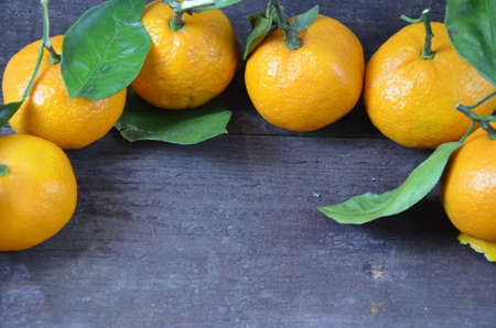 Tangerines oranges, mandarins, clementines, citrus fruits with leaves on the rustic wooden background, copy space. winter.の写真素材