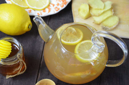 Teapot of ginger tea with honey and lemon on wooden tableの写真素材