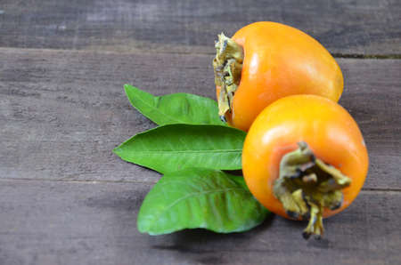 Delicious ripe persimmon fruit on wooden backgroundの写真素材