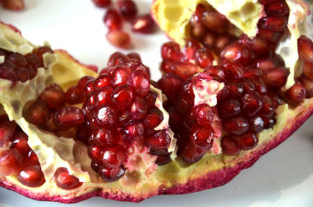 Big Ripe Red Granets or Garnets. Cut pomegranate and seeds. Fruits of Red Ripe Pomegranate on the White Background. Vegetarian Concept, Organic Vitamins, Detox. Organic and Benefit Garnet Fruit. Grains of Ripe Pomegranate.の写真素材