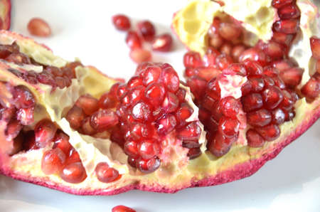 Big Ripe Red Granets or Garnets. Cut pomegranate and seeds. Fruits of Red Ripe Pomegranate on the White Background. Vegetarian Concept, Organic Vitamins, Detox. Organic and Benefit Garnet Fruit. Grains of Ripe Pomegranate.の写真素材