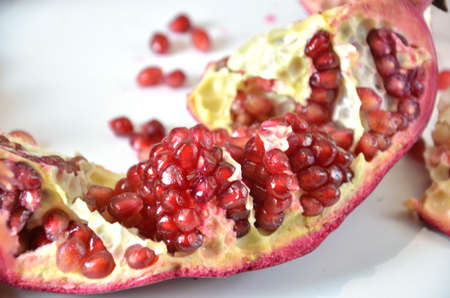 Big Ripe Red Granets or Garnets. Cut pomegranate and seeds. Fruits of Red Ripe Pomegranate on the White Background. Vegetarian Concept, Organic Vitamins, Detox. Organic and Benefit Garnet Fruit. Grains of Ripe Pomegranate.の写真素材