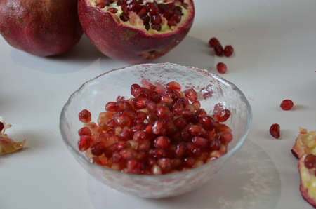 Bowl of fresh red pomegranate seeds on white backgroundの写真素材