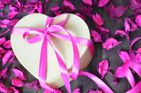 a gift for the day of the holy Valentine. box in the shape of the heart. lilac, raspberry petals red background. textureの写真素材