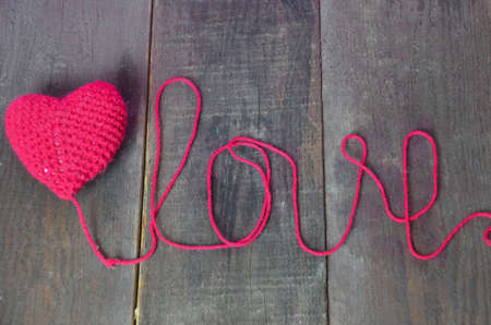 Close up red crochet heart isolated on wooden background. Love and care concepts. Valentine's day.の写真素材